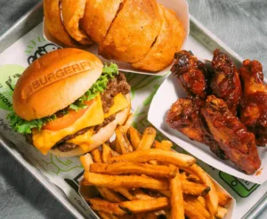 A tray featuring a hamburger, sweet potato fries, BBQ chicken wings, and fried dough bites.