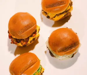 Four mini hamburgers with branded buns arranged neatly on a white surface.