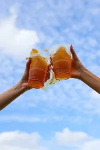 Cheers with refreshing beer under a clear blue sky – perfect pairing after finding the best burgers near me.