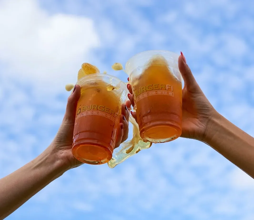 Cheers with refreshing drinks under a clear blue sky – perfect pairing after finding the best burgers near me.