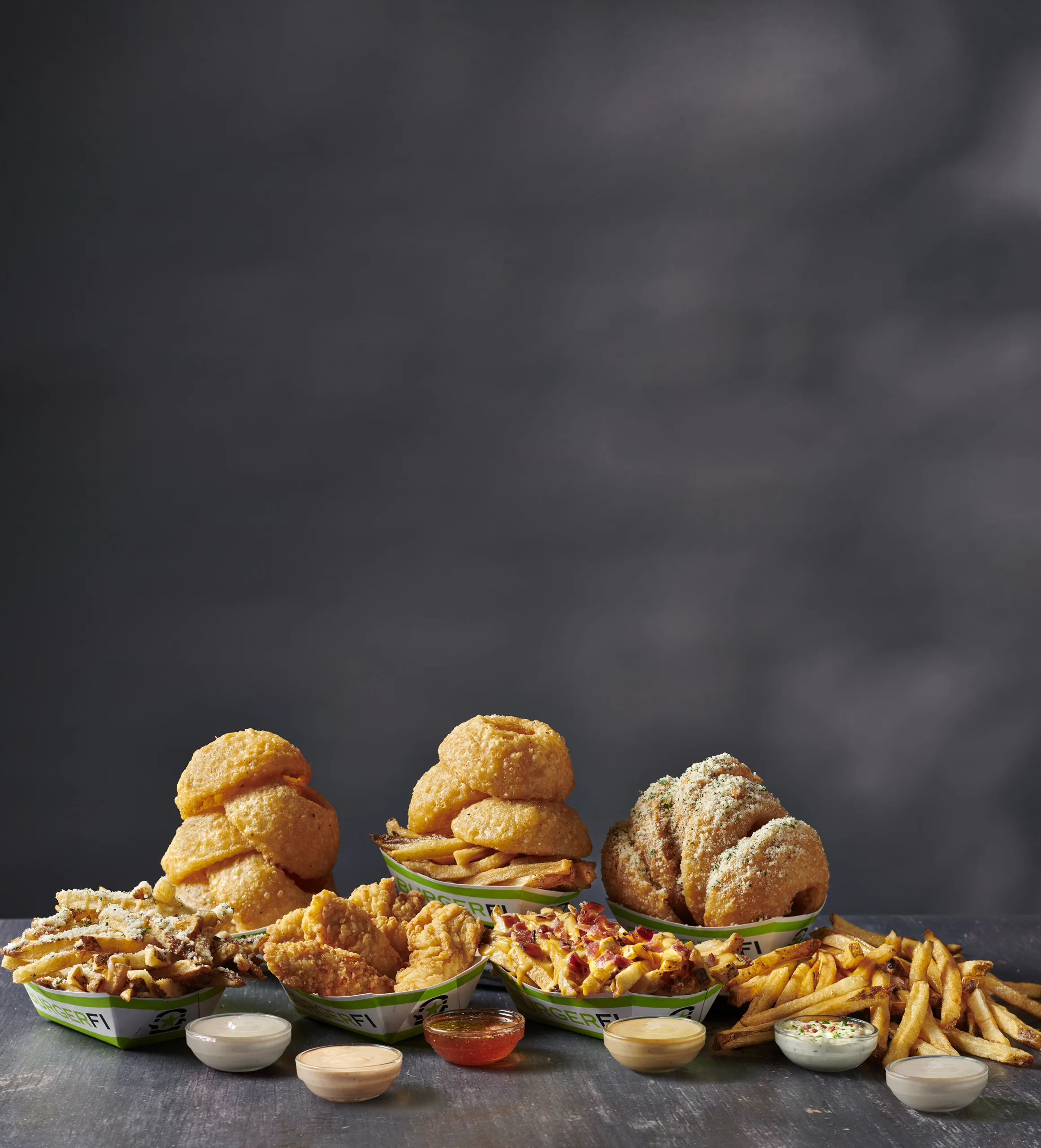 A variety of crispy sides, including french fries, onion rings, and chicken tenders, served with dipping sauces.