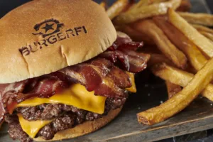 A close-up shot of a delicious double cheeseburger with bacon and a side of fries from BurgerFi.