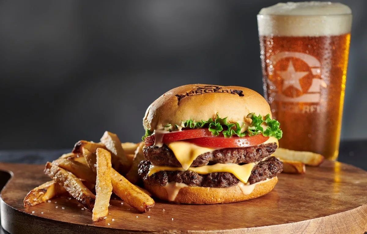 A BurgerFi meal — juicy cheeseburger, a glass of Cola, and crispy fries.
