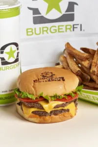 A double cheeseburger with two beef patties, cheese, lettuce, tomato, and onion on a bun, served with a side of french fries.