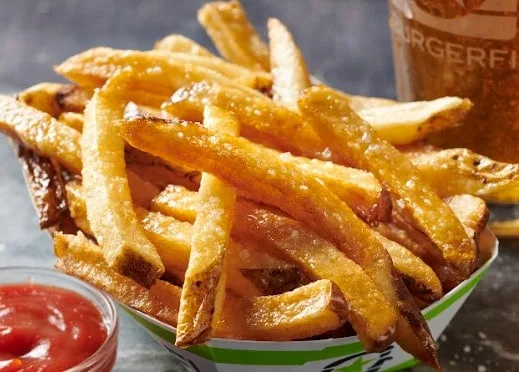 A basket of crispy, golden French fries with a side of ketchup.