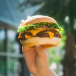 A hand holding up a juicy BurgerFi burger