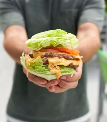 A hand holding a juicy burger from BurgerFi.