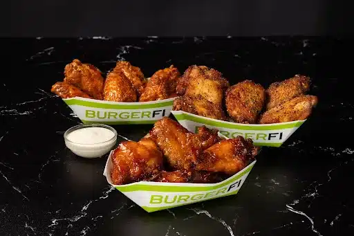 Various kinds of chicken wings served at BurgerFi are placed on a marble top.